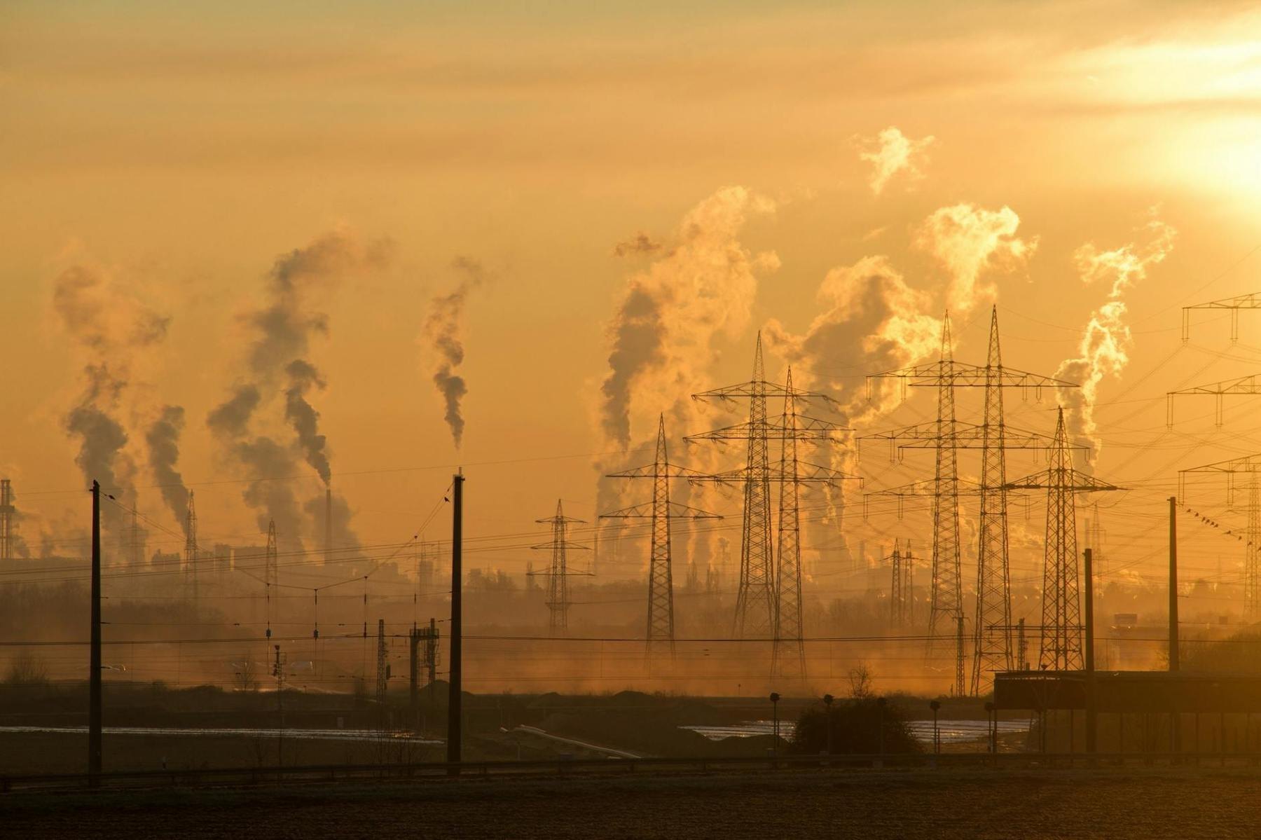 Smokestacks releasing pollution into an orange sky