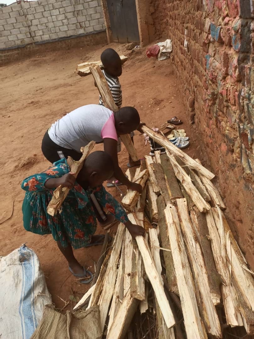 Children stacking firewood beside the Love Uganda Foundation home